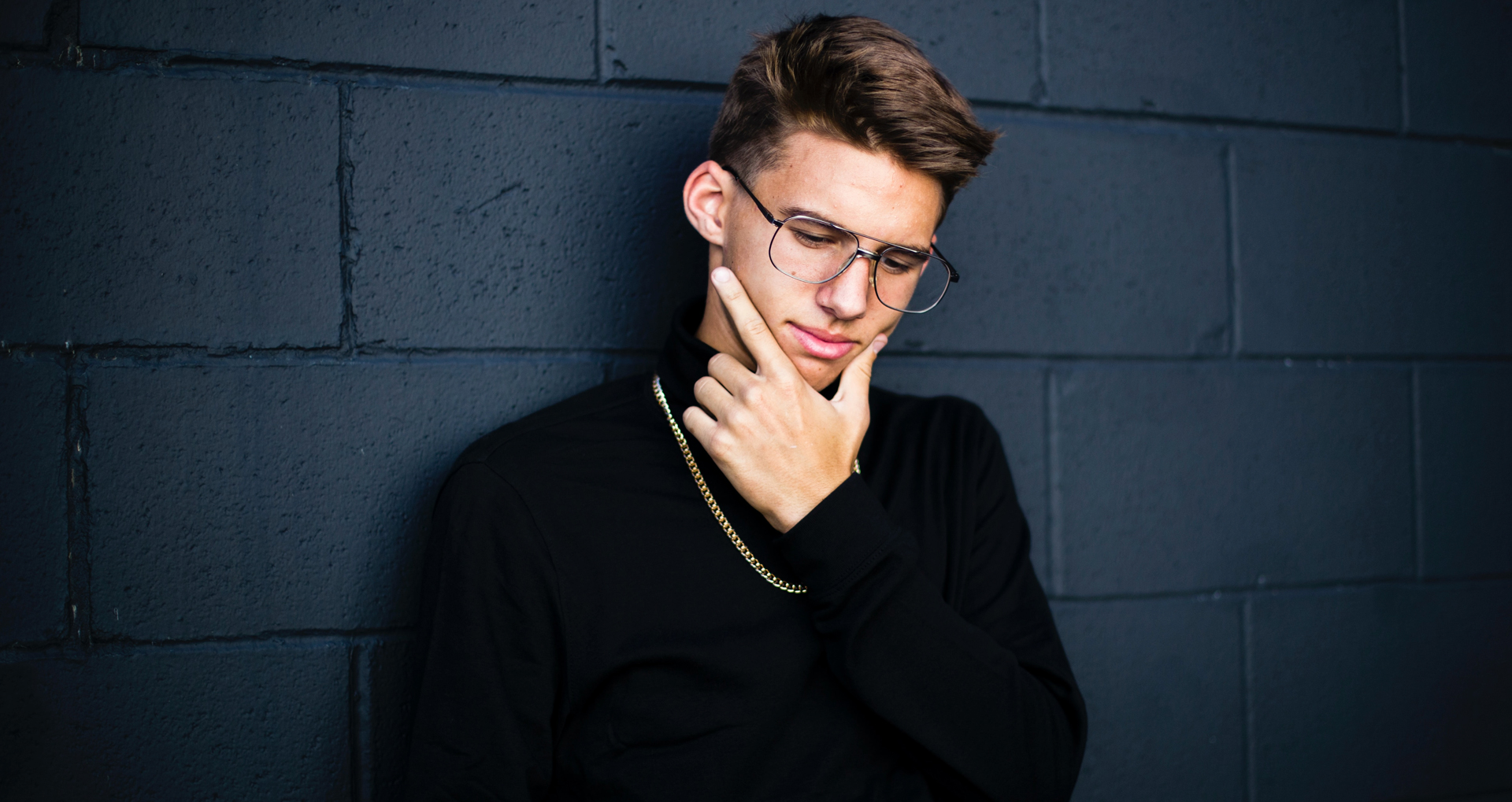 young man leaning on blue wall thinking