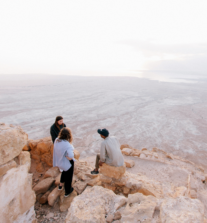 Personal Coaching and Therapy with 3 people sitting on rocks looking out over beach to the ocean horizon