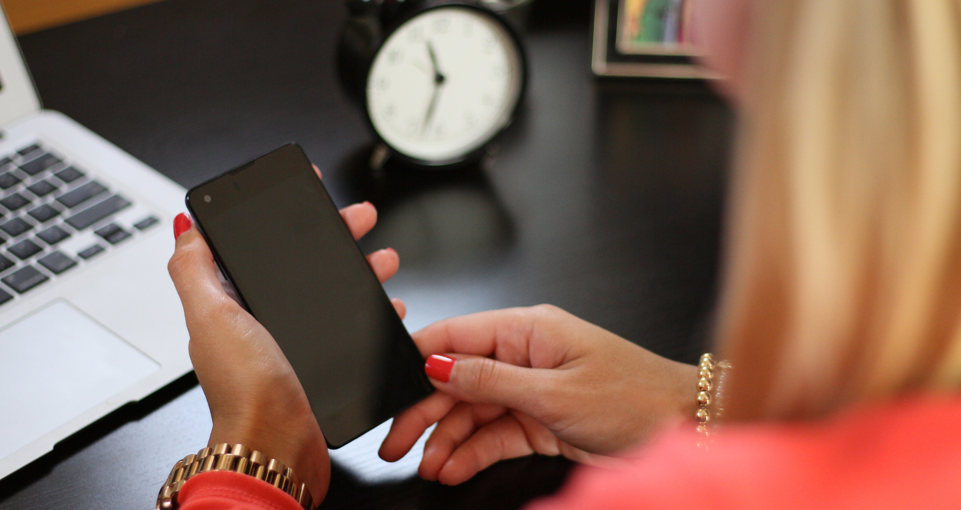 close up of woman at desk with phone in her hand